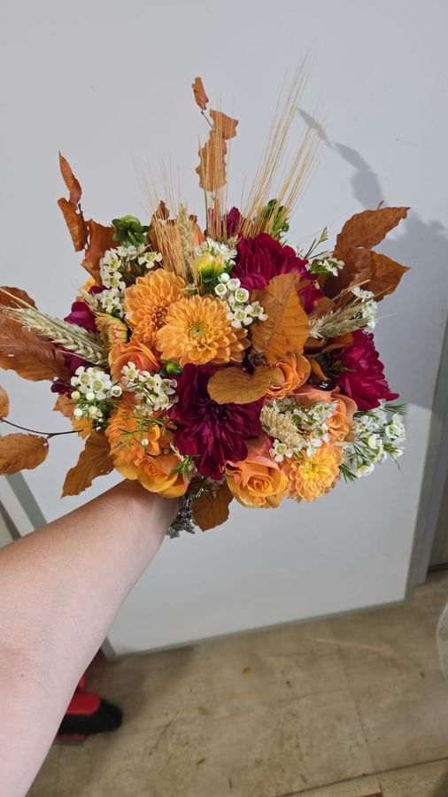 Bouquet autunnale con dalie arancioni e fucsia, rose, spighe di grano e foglie secche