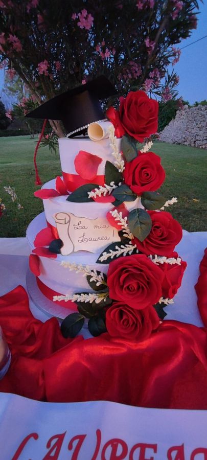 Torta di laurea a tre piani decorata con rose rosse, tocco accademico e pergamena con scritta "La mia Laurea"