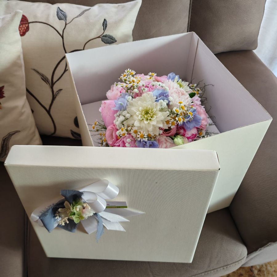 Flower box bianca con rose rosa, crisantemo bianco, camomilla e delphinium azzurro, con coperchio decorato da fiocco